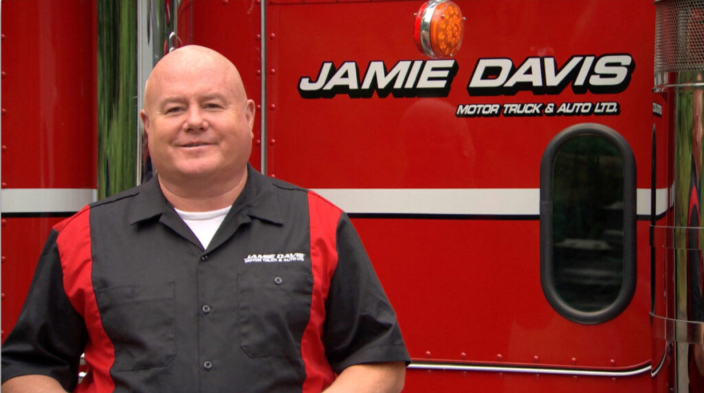 jamie davis standing next to a red jamie davis tow truck