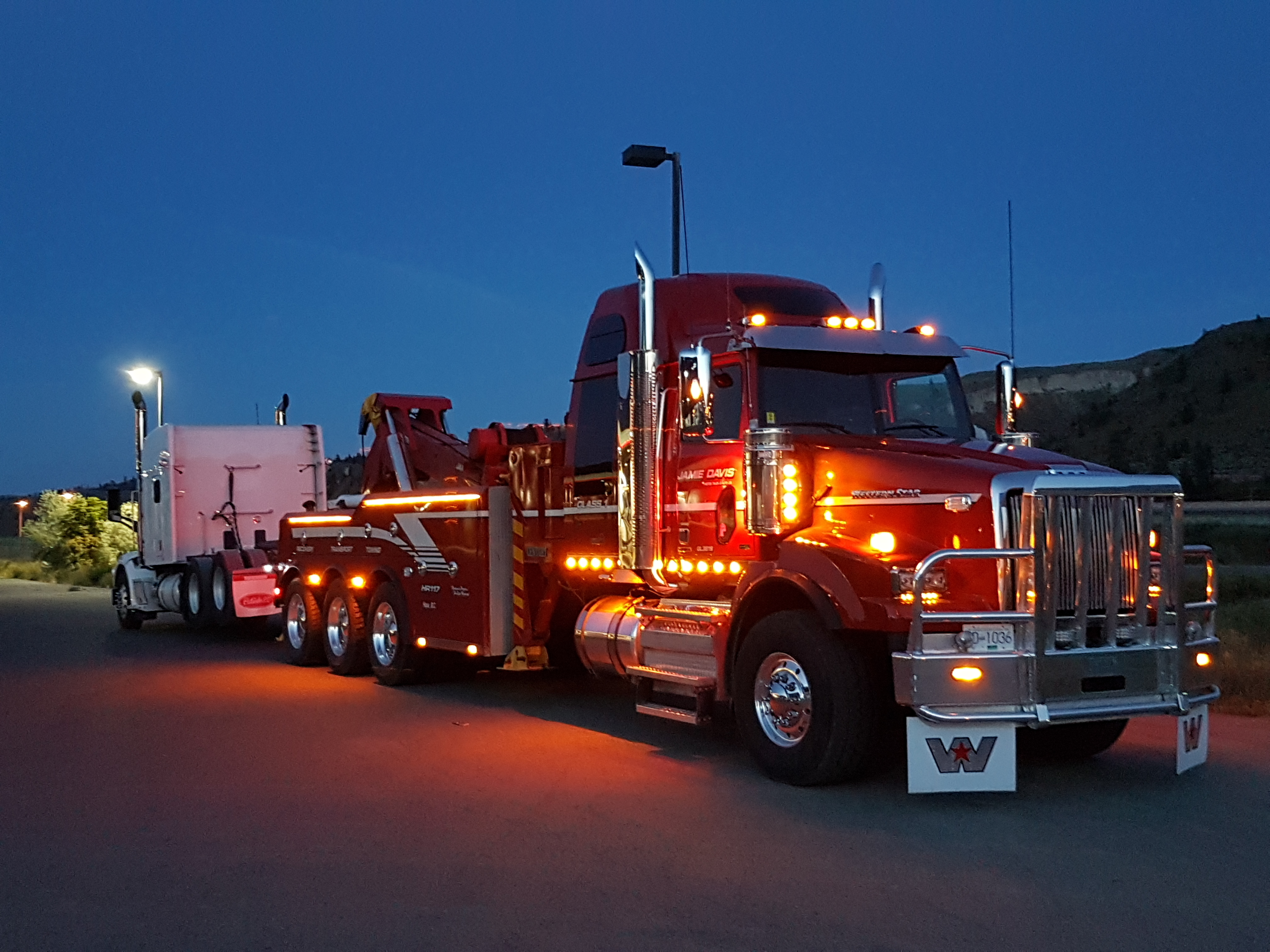 jamie davis red commercial tow truck with lights on at night