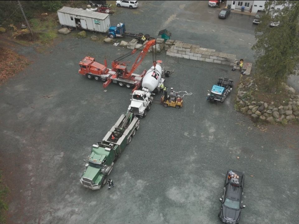 Jamie Davis' Commercial Towing Team using a crane to lift a cement truck onto a heavy-duty towing trailer